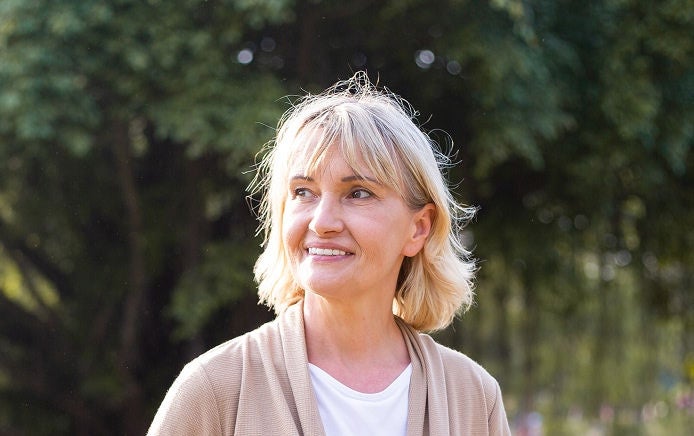 Una mujer se encuentra al aire libre, bajo el sol, y sonríe, consciente de que cuenta con el respaldo de la gama de suplementos nutricionales de Fresubin. 