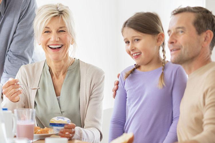 Familie beim gemeinsamen Essen. Eine Dysphagie-Patientin nimmt Fresubin Crème zu sich - verlinkt zu Produktfinder