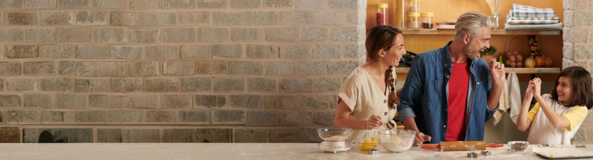Gezin met vrouw, man en kind dat samen al lachend aan het koken is in de keuken