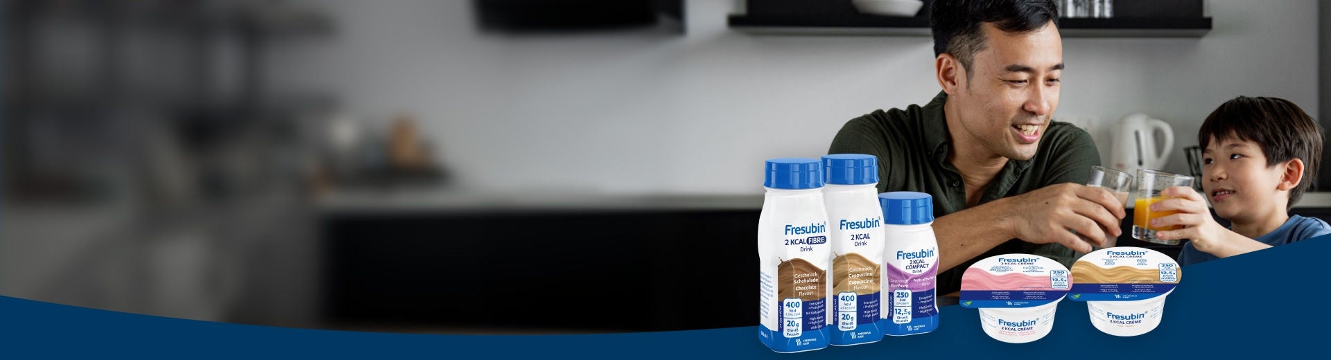 A smiling man sits with a young boy at a kitchen counter, with the Fresubin 2KCAL product range displayed in the foreground, including Fresubin Chocolate-flavoured 2KCAL FIBRE Drink, Fresubin Cappuccino-flavoured 2KCAL Drink, Forest Fruits 2KCAL COMPACT Drink, and 2KCAL Crème in Wild Strawberry and Praline flavours. 