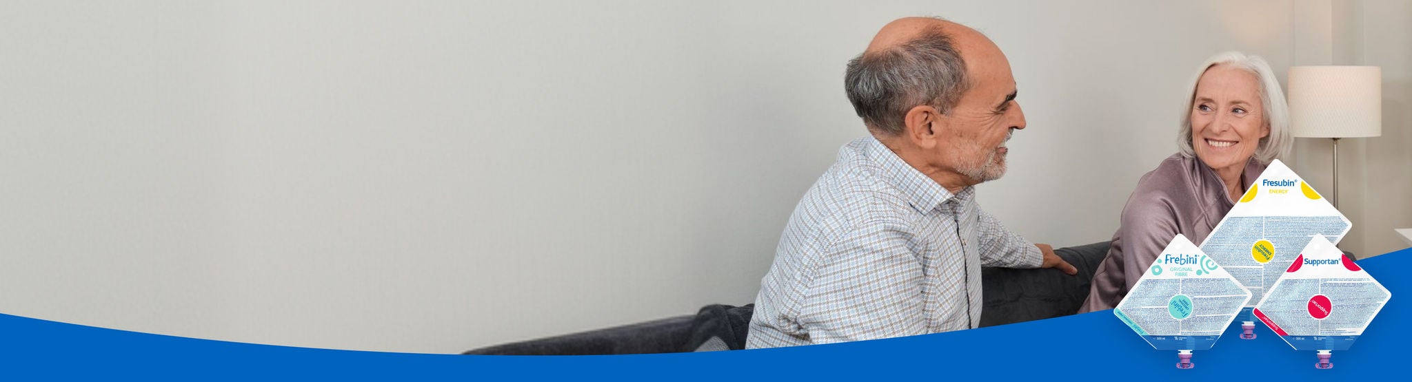 An older man and woman on a sofa smile at each other knowing they are supported by Fresbin's Tube Feed range, which includes Frebini ORIGINAL FIBRE, Fresubin ENERGY and Supportan Tube Feeds. 