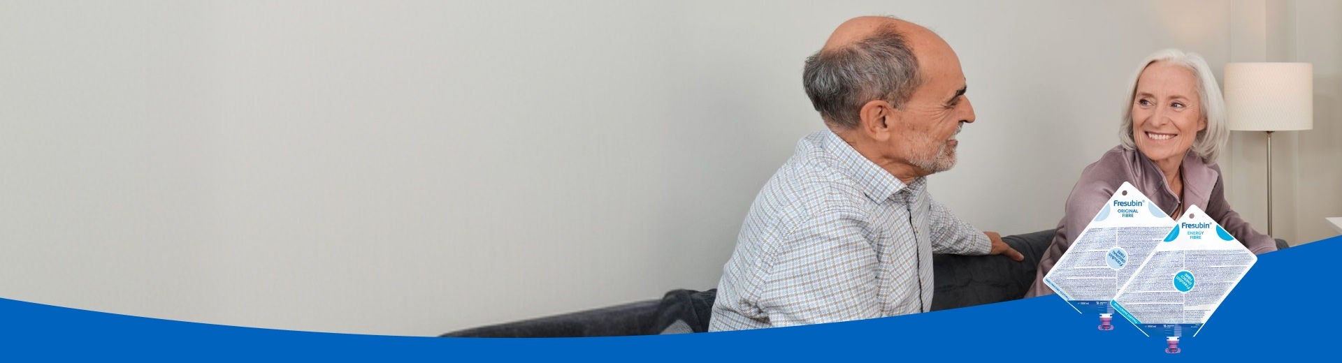 An older man and woman on a sofa smile at each other knowing they are supported by Fresbin's Tube Feed range, which includes Frebini ORIGINAL FIBRE, Fresubin ENERGY and Supportan Tube Feeds. 