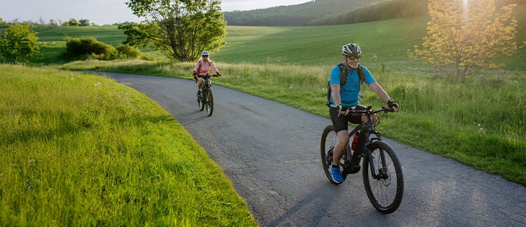 žmonės važiuoja dviračiu užmiestyje