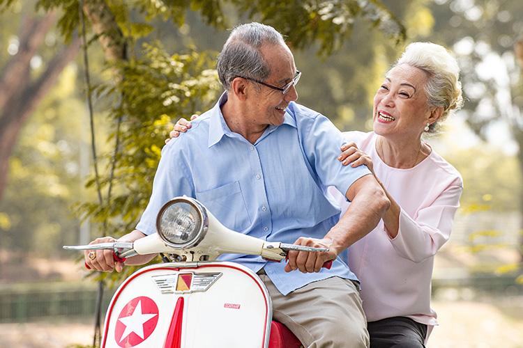Seniors on vespa smiling at each other