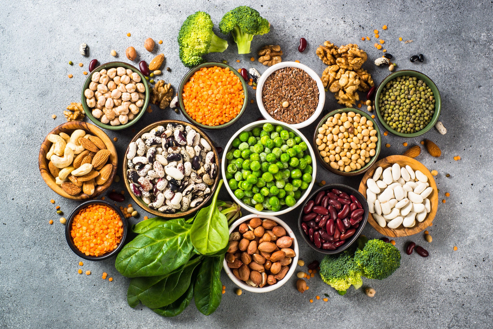 Vegan protein source. Legumes, beans, lentils, nuts, broccoli, spinach and seeds. Top view on stone table. Healthy vegetarian food.