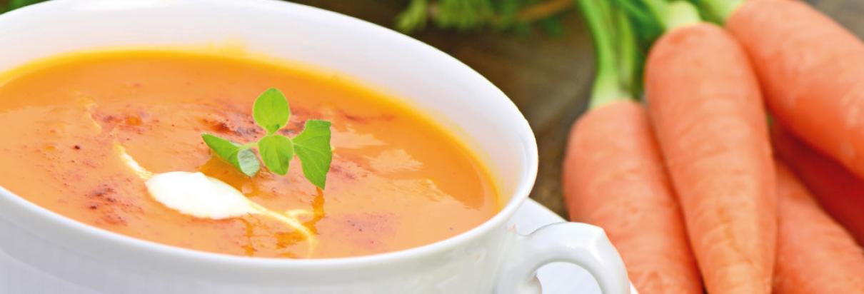 Karottensuppe in einer Suppenschüssel mit Karotten nebendran