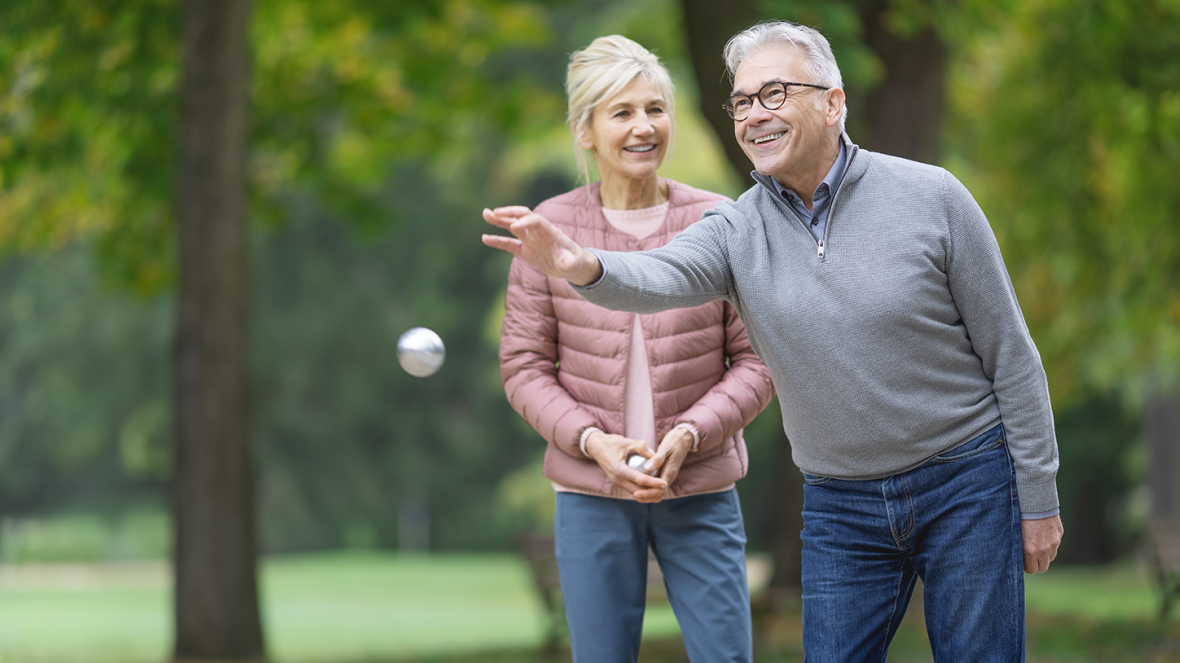 Ein älteres Ehepaar spielt Boule, um sich körperlich fit zu halten.