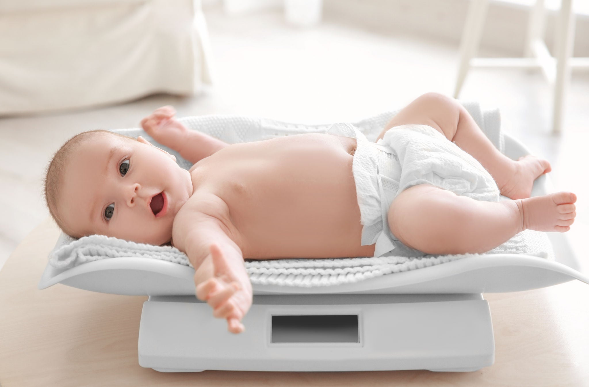 Cute little baby lying on scales at home Cute little baby lying on scales at home