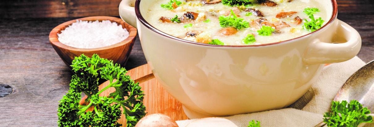 Rahmchampignons in einer Keramik-Suppenschüssel mit beiliegendem Gemüse und Salz