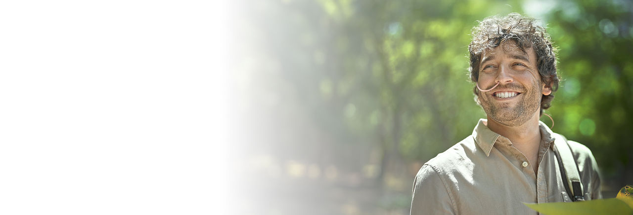 Mann mit Sonde in der Nase lächelt im Wald.