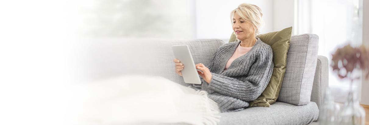 Patientin liegt auf dem Sofa und stellt eine Anfrage online.