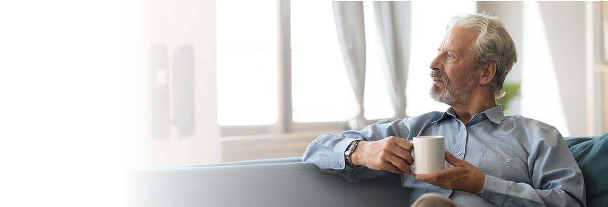 vyras laiko puodelį ir žiūri į šoną