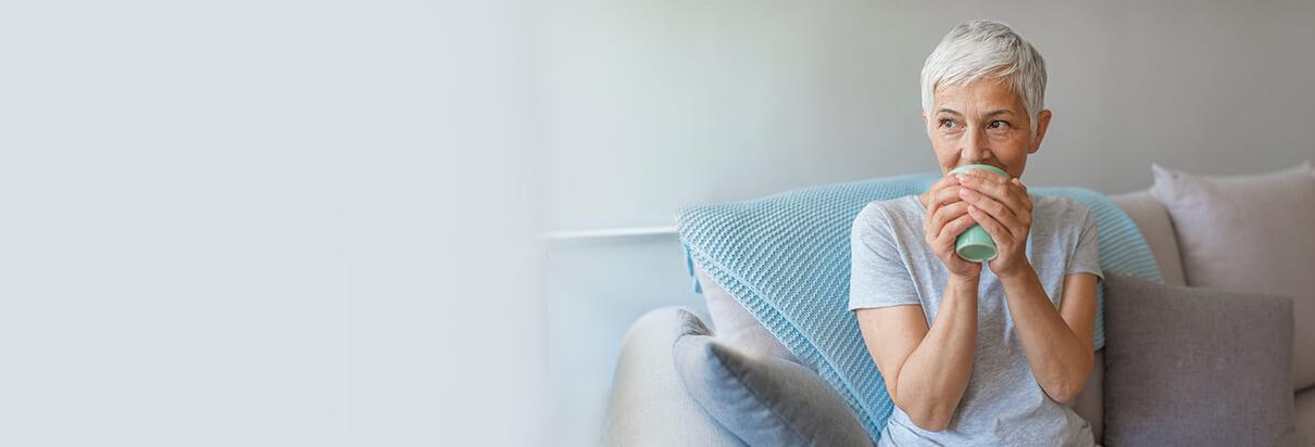 kvinne som sitter i sofa og holder en kopp
