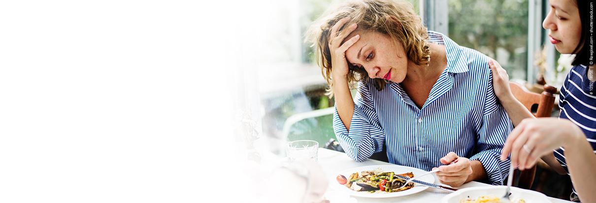 Appetitlosigkeit - Frau ist über ihr Essen gebeugt und hat keinen Appetit.